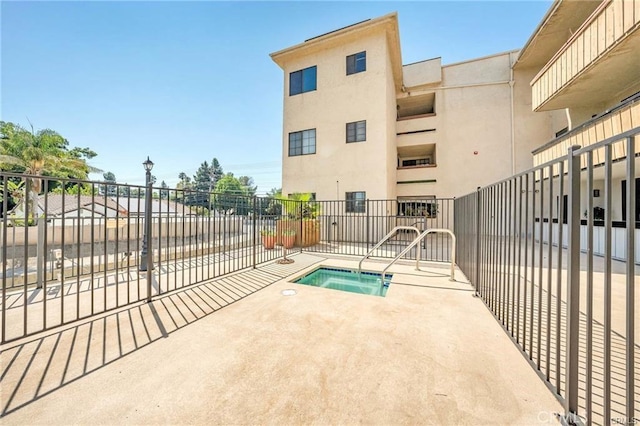 view of swimming pool featuring a patio area, fence, and a community hot tub