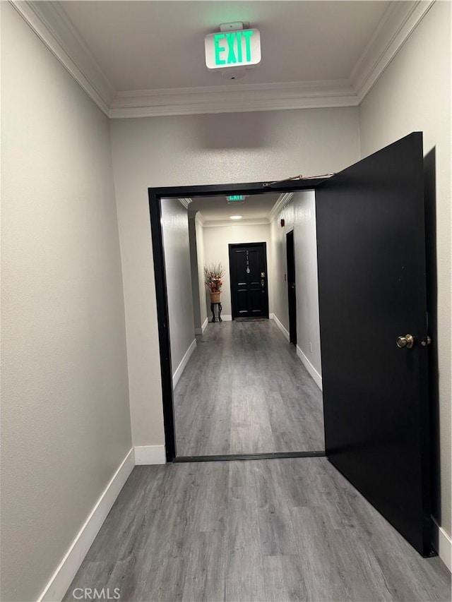 corridor with ornamental molding, baseboards, and wood finished floors