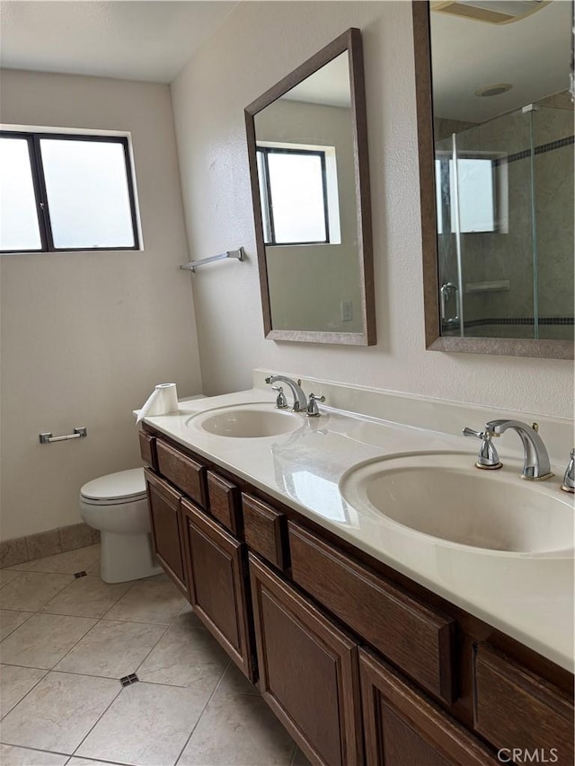 bathroom with a shower with shower door, a healthy amount of sunlight, and a sink
