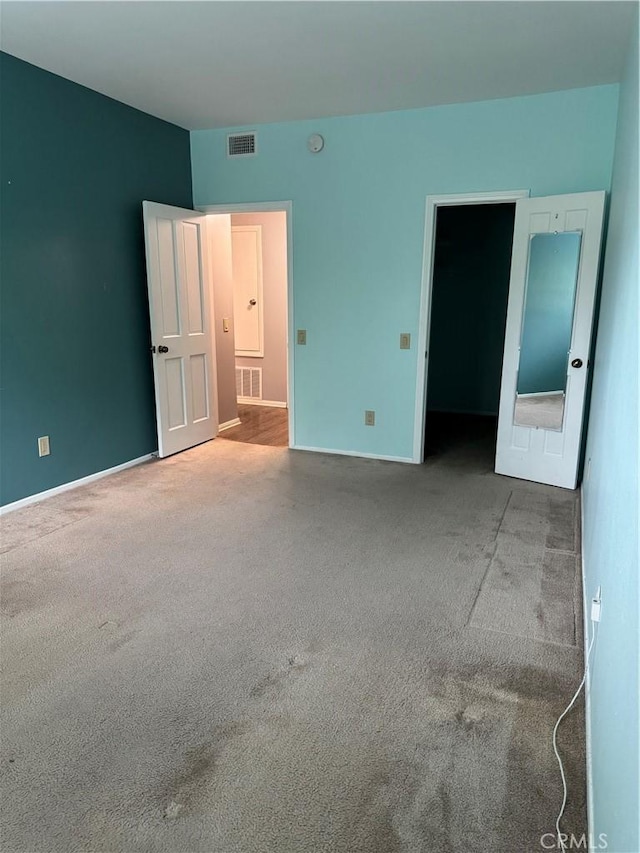 unfurnished bedroom featuring baseboards, carpet flooring, and visible vents