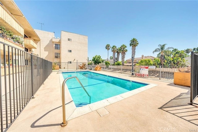 community pool with a patio area and fence
