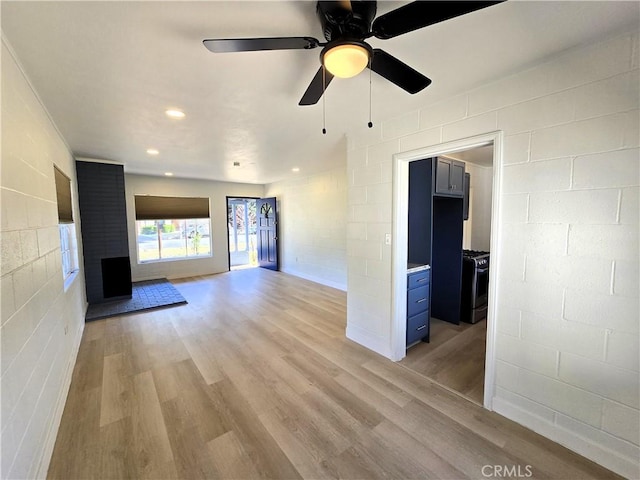 unfurnished living room with a ceiling fan, light wood-style flooring, recessed lighting, and concrete block wall