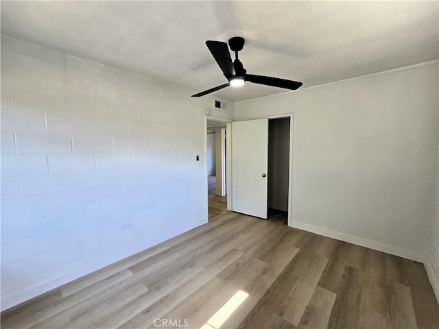 empty room with visible vents, wood finished floors, baseboards, and ceiling fan
