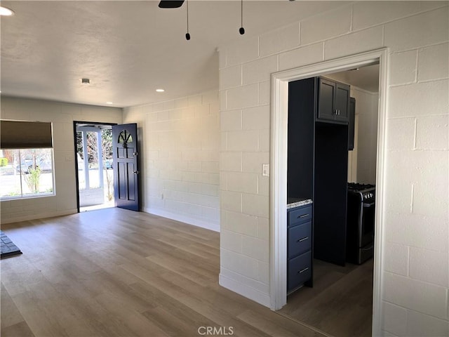 unfurnished room with concrete block wall, wood finished floors, a ceiling fan, and recessed lighting