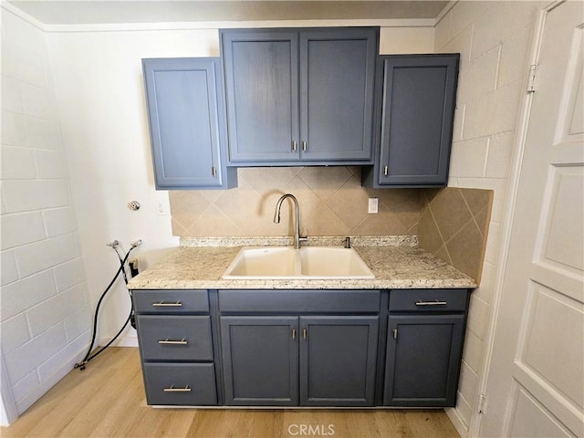 kitchen featuring gray cabinetry, light wood-style floors, tasteful backsplash, and a sink