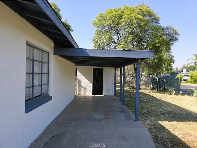 exterior space featuring concrete block siding and a carport
