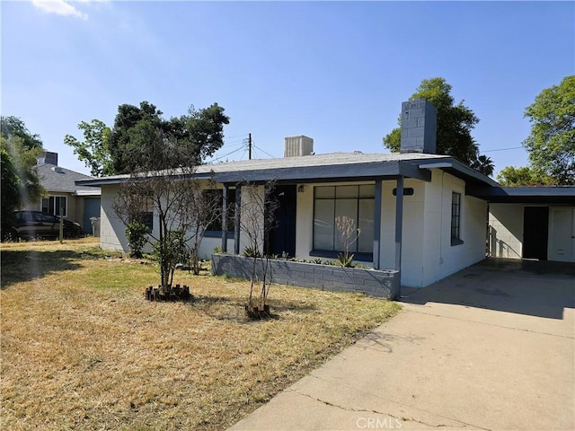 ranch-style house featuring a chimney, driveway, and a front lawn
