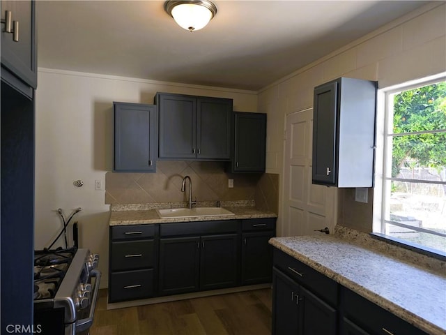 kitchen with a sink, dark wood finished floors, crown molding, backsplash, and stainless steel range