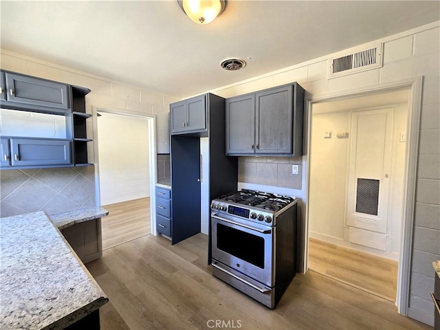 kitchen featuring gas stove, light stone counters, visible vents, and wood finished floors