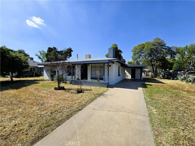 ranch-style home featuring a front lawn, stucco siding, driveway, and a chimney