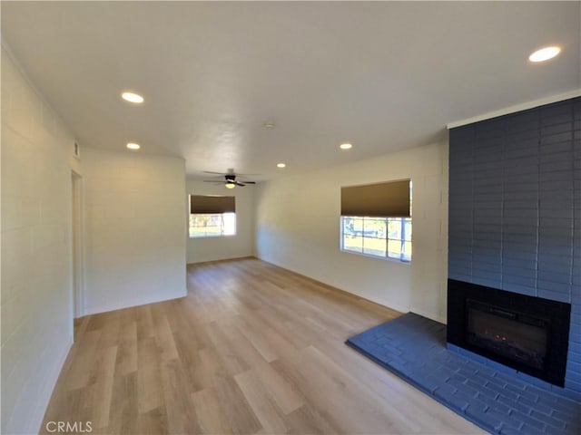 unfurnished living room with recessed lighting, ceiling fan, light wood-type flooring, and a large fireplace