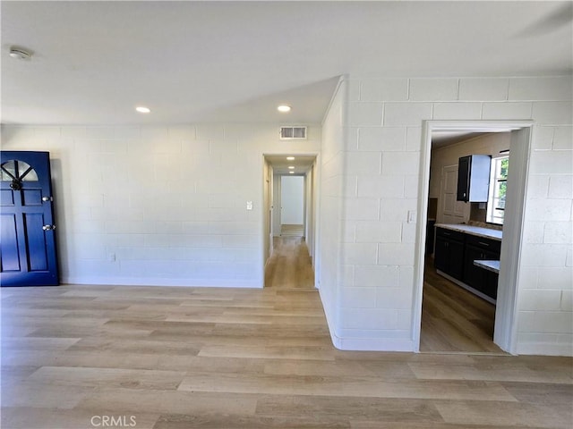 unfurnished room with light wood finished floors, visible vents, and concrete block wall