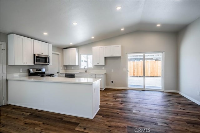 kitchen featuring a peninsula, stainless steel appliances, white cabinets, light countertops, and lofted ceiling
