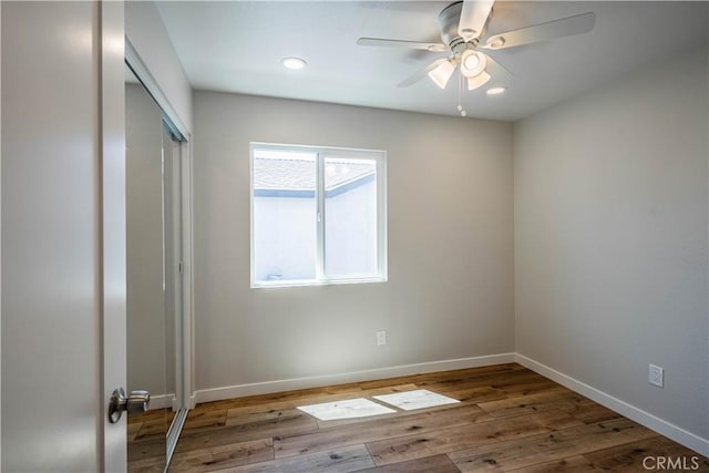 unfurnished bedroom with wood finished floors, a ceiling fan, a closet, baseboards, and recessed lighting