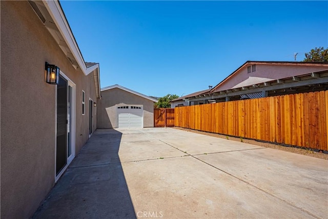 view of side of property featuring concrete driveway, stucco siding, and fence