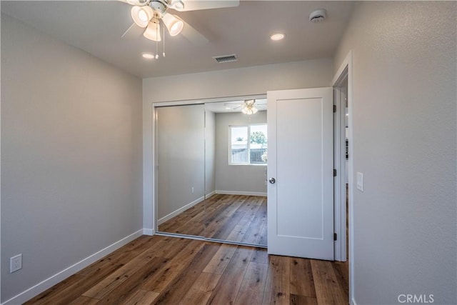 unfurnished bedroom featuring a closet, recessed lighting, baseboards, wood-type flooring, and visible vents