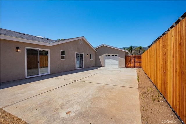 rear view of property with a patio area, stucco siding, a garage, and a fenced backyard