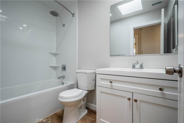 full bathroom with a skylight, toilet, wood finished floors, vanity, and visible vents