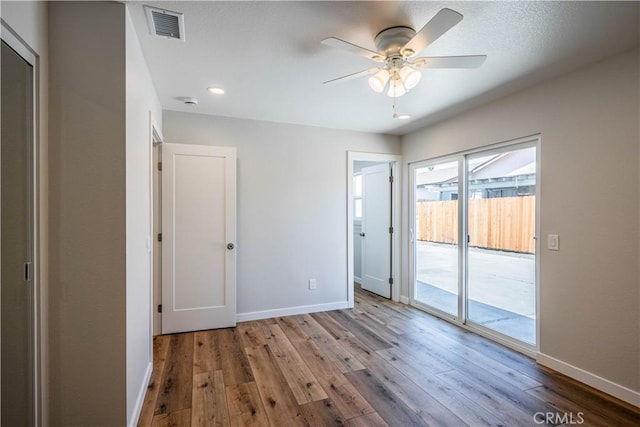 unfurnished bedroom with wood finished floors, visible vents, baseboards, and access to exterior