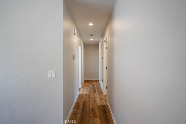 hall with wood finished floors, baseboards, and recessed lighting