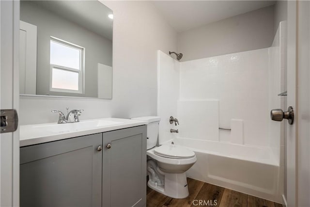 bathroom featuring toilet, tub / shower combination, wood finished floors, and vanity