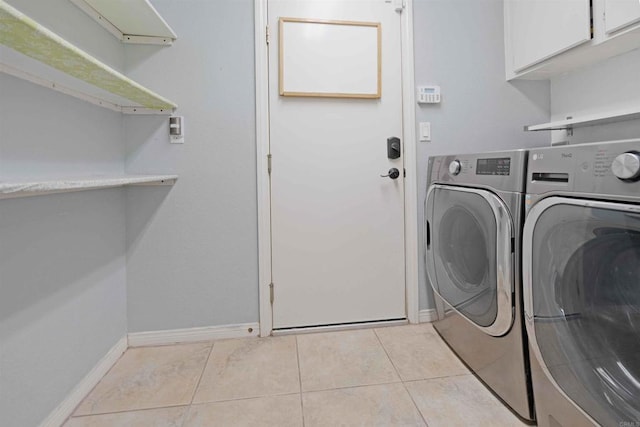 laundry room featuring baseboards, light tile patterned floors, washer and dryer, and cabinet space