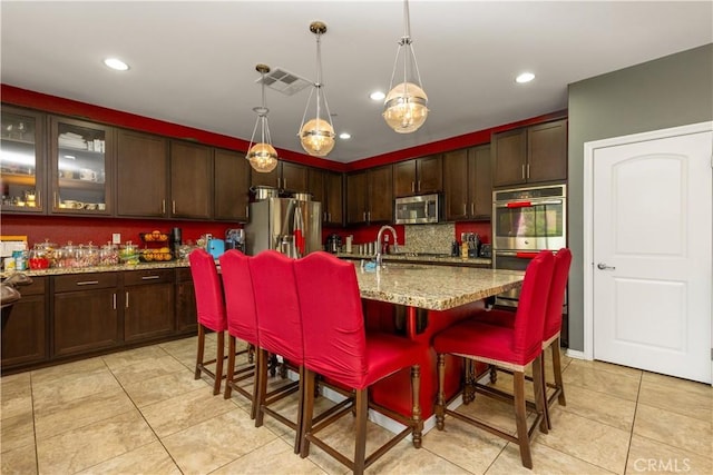 36696 Pavic Ct, Lake Elsinore, CA 92532 - kitchen featuring stainless steel appliances, light tile patterned floors, dark brown cabinetry, a kitchen bar, and recessed lighting