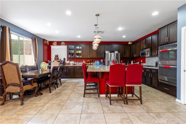 36696 Pavic Ct, Lake Elsinore, CA 92532 - kitchen with appliances with stainless steel finishes, dark brown cabinetry, recessed lighting, a kitchen island, and pendant lighting