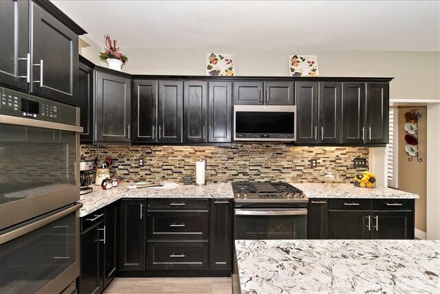 4990 Padre Ave, Rancho Cucamonga, CA 91739 - kitchen featuring dark cabinetry, backsplash, and appliances with stainless steel finishes