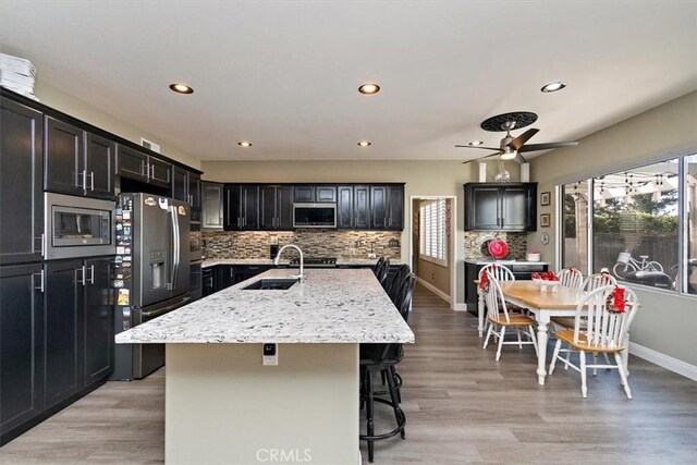 4990 Padre Ave, Rancho Cucamonga, CA 91739 - kitchen featuring a center island with sink, stainless steel appliances, tasteful backsplash, and recessed lighting