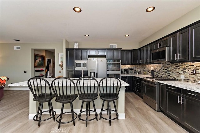 4990 Padre Ave, Rancho Cucamonga, CA 91739 - kitchen with dark cabinets, a kitchen breakfast bar, light wood-type flooring, and appliances with stainless steel finishes