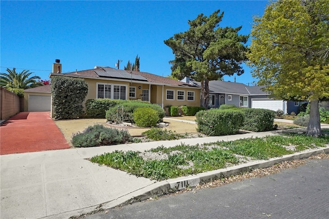 7111 Texhoma Ave, Van Nuys, CA 91406 - single story home with stucco siding, solar panels, a garage, driveway, and a chimney
