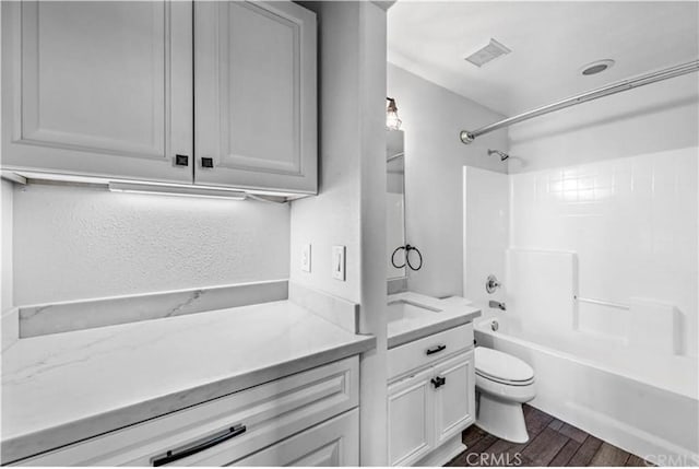 full bathroom featuring toilet, shower / tub combination, wood finished floors, vanity, and visible vents