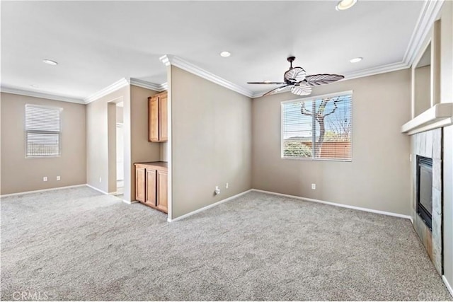unfurnished living room with ornamental molding, a glass covered fireplace, recessed lighting, and light colored carpet