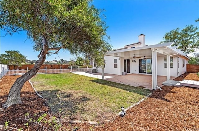 back of house with a patio, a chimney, a fenced backyard, ceiling fan, and a yard