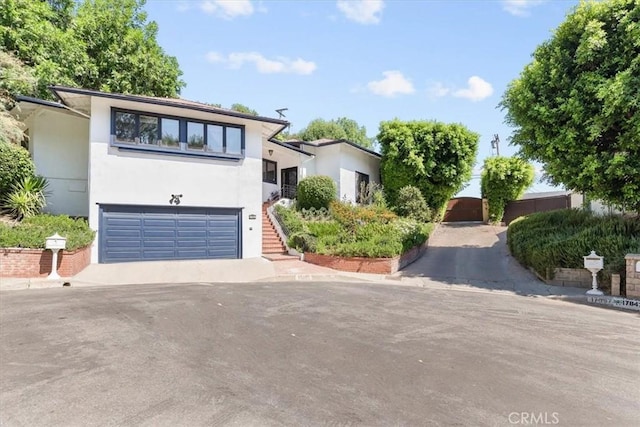 17861 Cathedral Pl, Encino, CA 91316 - view of front of house with stucco siding, an attached garage, driveway, and stairway