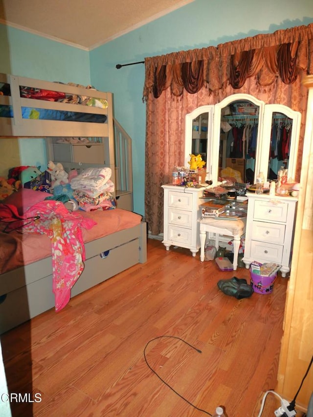 bedroom with ornamental molding and wood finished floors