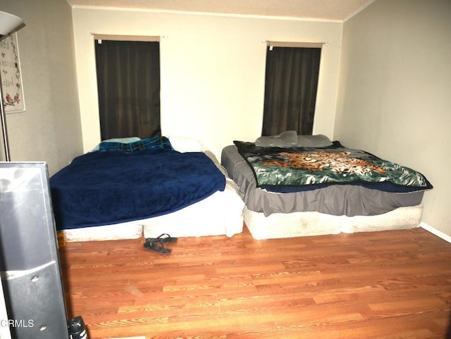 bedroom with ornamental molding, baseboards, and wood finished floors