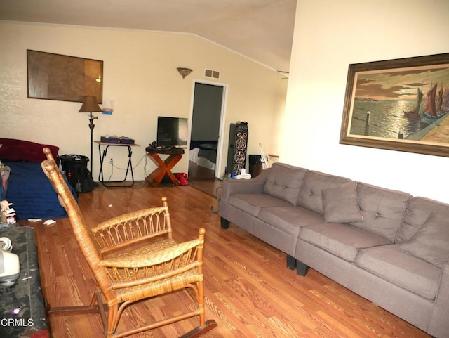 living area featuring lofted ceiling, visible vents, and wood finished floors