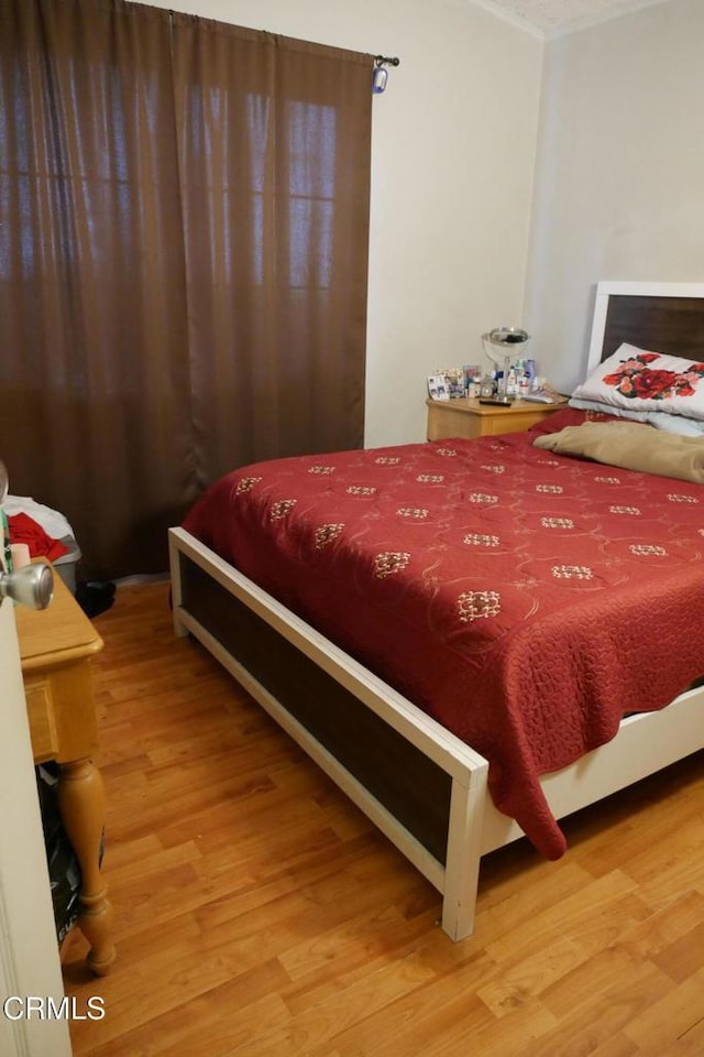bedroom featuring light wood-style floors and crown molding