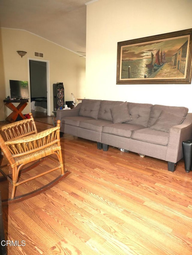 living room featuring lofted ceiling, visible vents, and wood finished floors
