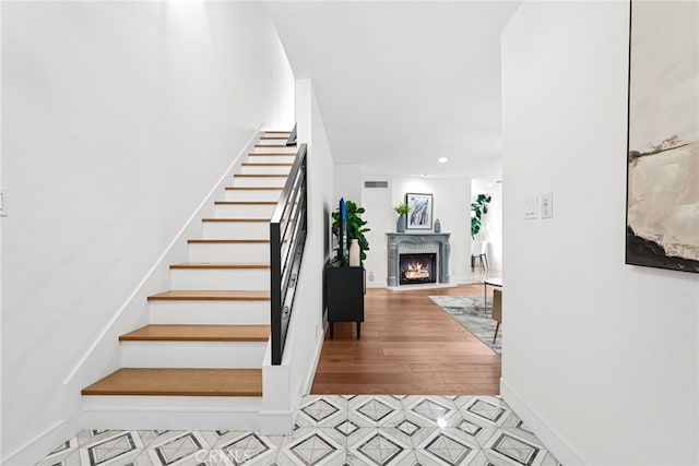 stairs with baseboards, a warm lit fireplace, and recessed lighting