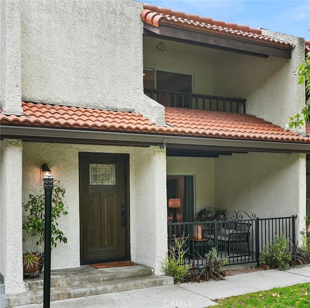 exterior space featuring stucco siding, a tile roof, and fence