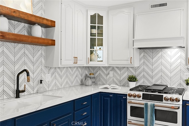 kitchen featuring visible vents, range with two ovens, blue cabinetry, and a sink