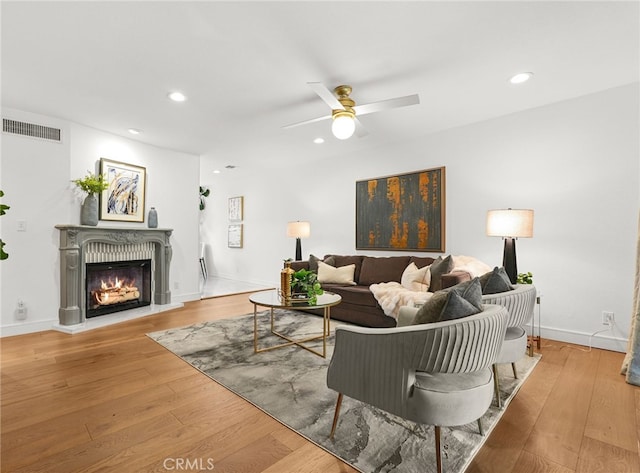 living room with a ceiling fan, recessed lighting, visible vents, a lit fireplace, and wood finished floors