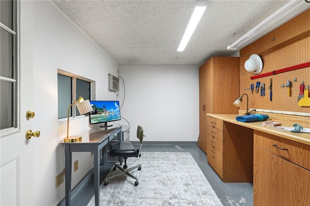 office featuring a textured ceiling, concrete flooring, and a workshop area