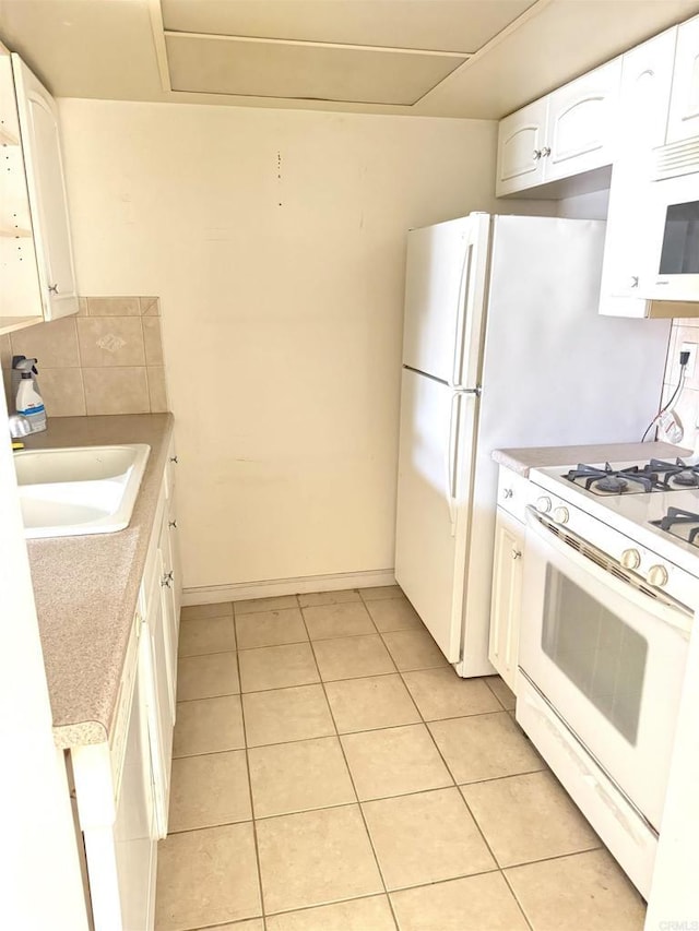 kitchen with white appliances, a sink, white cabinets, light tile patterned floors, and light countertops