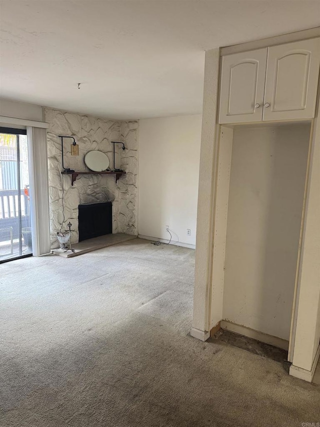 unfurnished living room with carpet, a fireplace, and baseboards