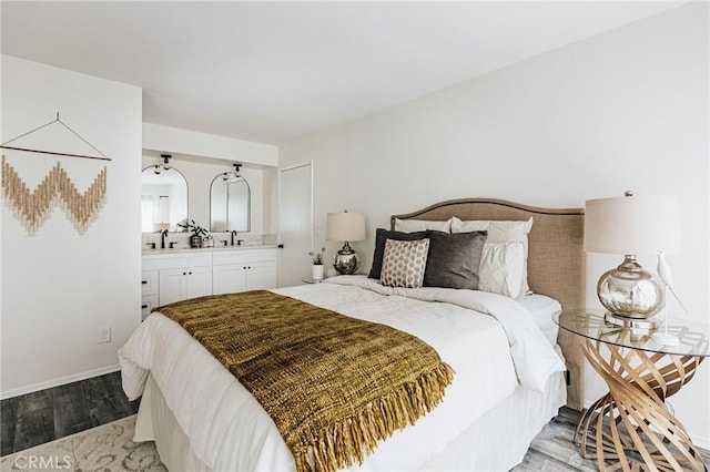 bedroom with a sink, light wood-style flooring, connected bathroom, and baseboards