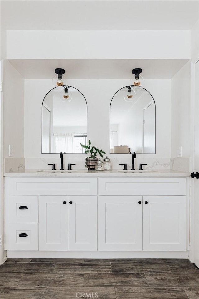 full bathroom with double vanity, wood finished floors, and a sink